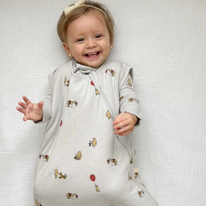 baby wearing gunamuna pooh sleep bag tog 2.5 smiling on white sheet