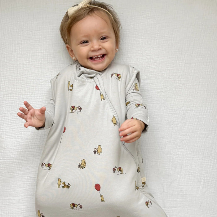 baby wearing gunamuna pooh sleep bag tog 2.5 smiling on white sheet