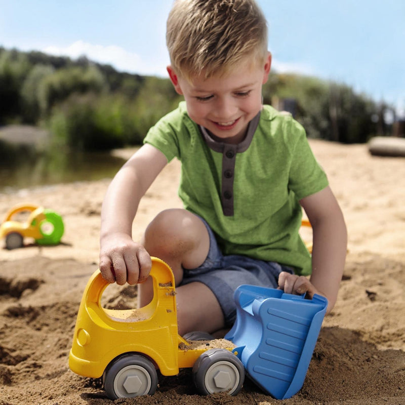 Child playing with toy cars and a shovel in the sand