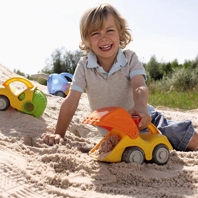 Child playing with a toy digger in the sand