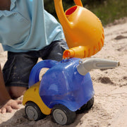 Child playing with a toy water pump and watering can in the sand