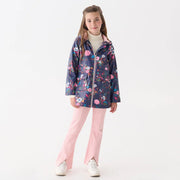 Girl wearing a floral raincoat and pink pants on a white background
