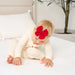 Baby wearing a red heirloom bow on a white bed