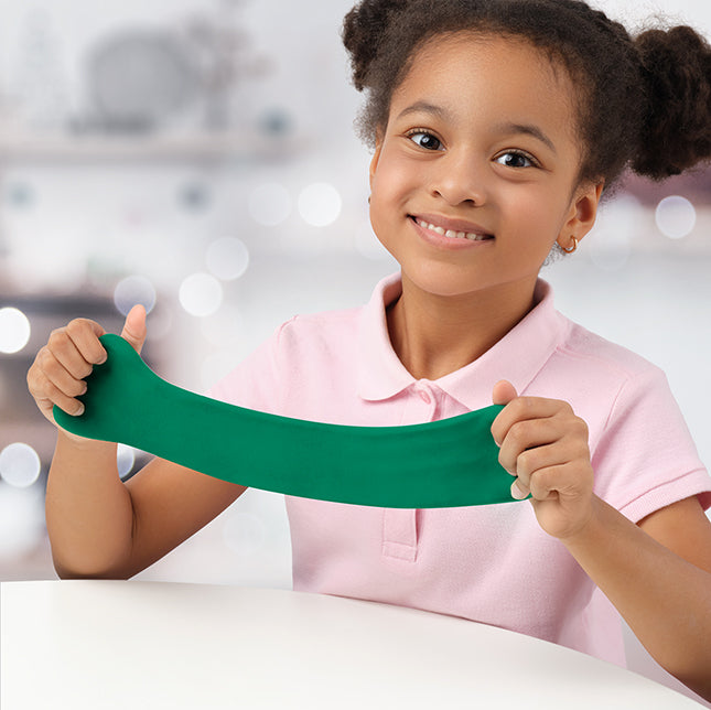 Child stretching bright green Hey Clay while smiling at a table