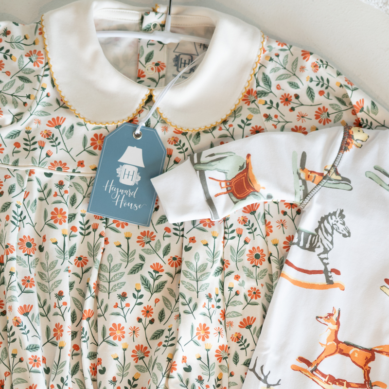 Children's dresses with floral and animal prints on hangers, featuring a 'Heyward House' tag.