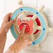 Child's hand turning a colorful toy steering wheel with a crab handle, a tile wall