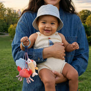Woman holding a baby outdoors with a toy, smiling