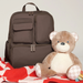 Brown backpack and teddy bear on a red blanket with a white background