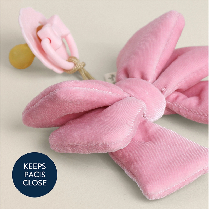 Pink velvet bow pacifier clip on a beige background