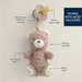 Teddy bear pacifier holder with features highlighted on a beige background