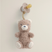 Teddy bear plush toy with a pacifier attached on a light beige background