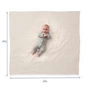 Baby in a gray onesie lying on a large striped mat with dimensions indicated.