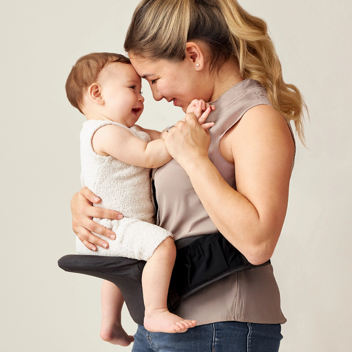 Woman holding a baby close together against a plain background