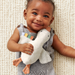 Baby holding a plush goose toy on a textured beige blanket