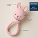Pink bunny-shaped teething ring with text on a beige background