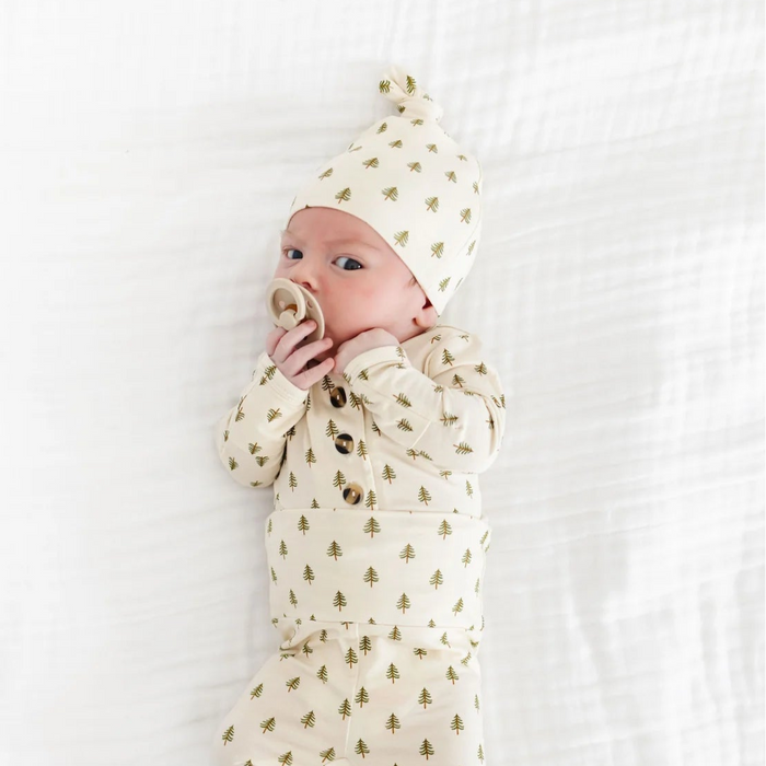 Baby in a white outfit with small patterns lying on a white surface