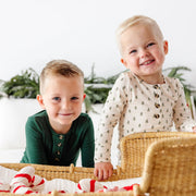 Two toddlers wearing Kevin Top and Bottoms in green and tree print sitting in a wicker basket