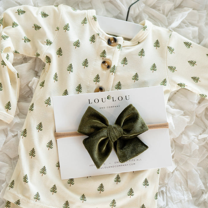 Baby outfit with green tree pattern and green bow headband on a white background