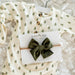 Baby outfit with green tree pattern and green bow headband on a white background