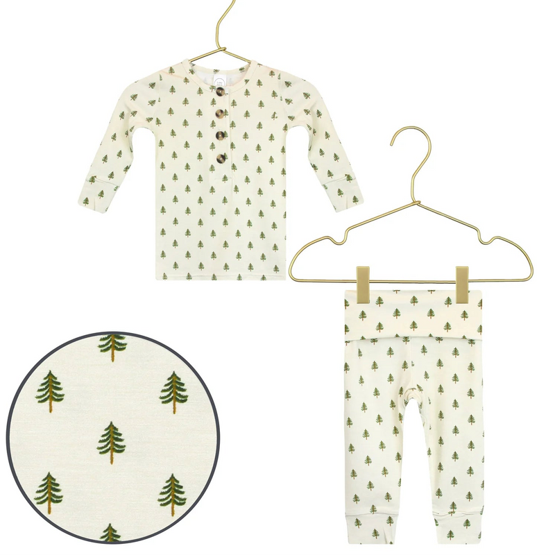 Children's long-sleeve shirt and pants with tree pattern on hangers against a white background.