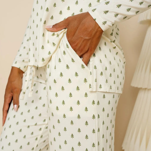 Person wearing a white outfit with green pattern, standing against a beige background