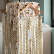 Hangers with tree patterned pajama pantson a rack against a neutral background