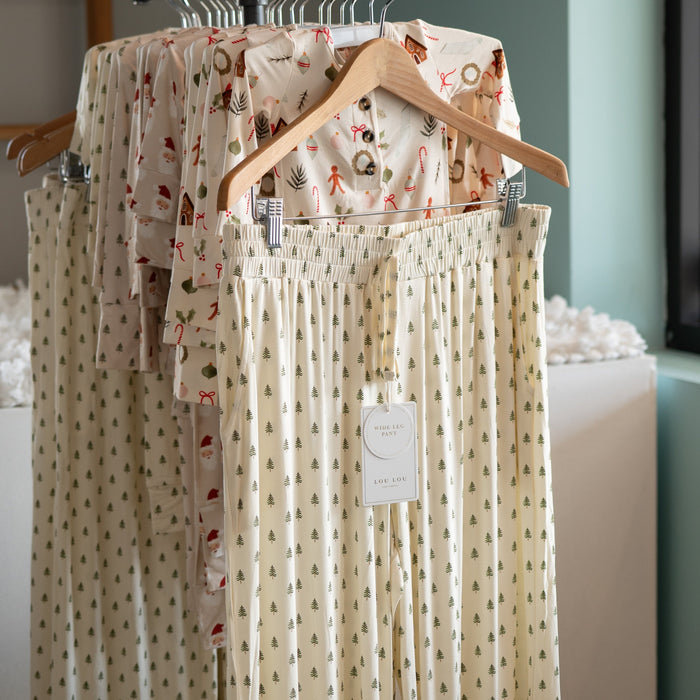 Hangers with tree patterned pajama pantson a rack against a neutral background