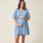 Pregnant woman wearing a light blue dress against a beige background