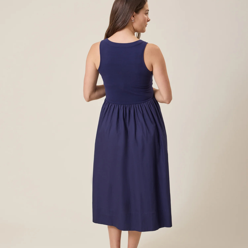 Woman wearing a navy blue dress against a beige background