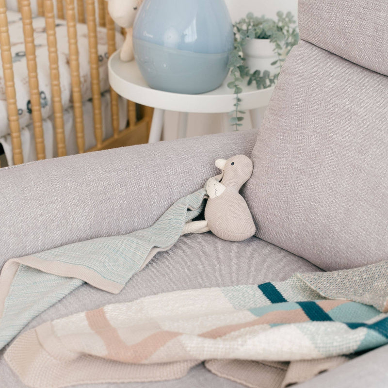 Gray sofa with a plush toy and baby blanket in a nursery setting