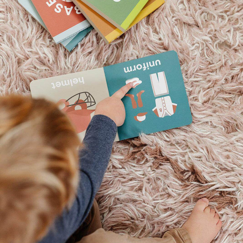 Child reading the Baseball Baby board book on a rug