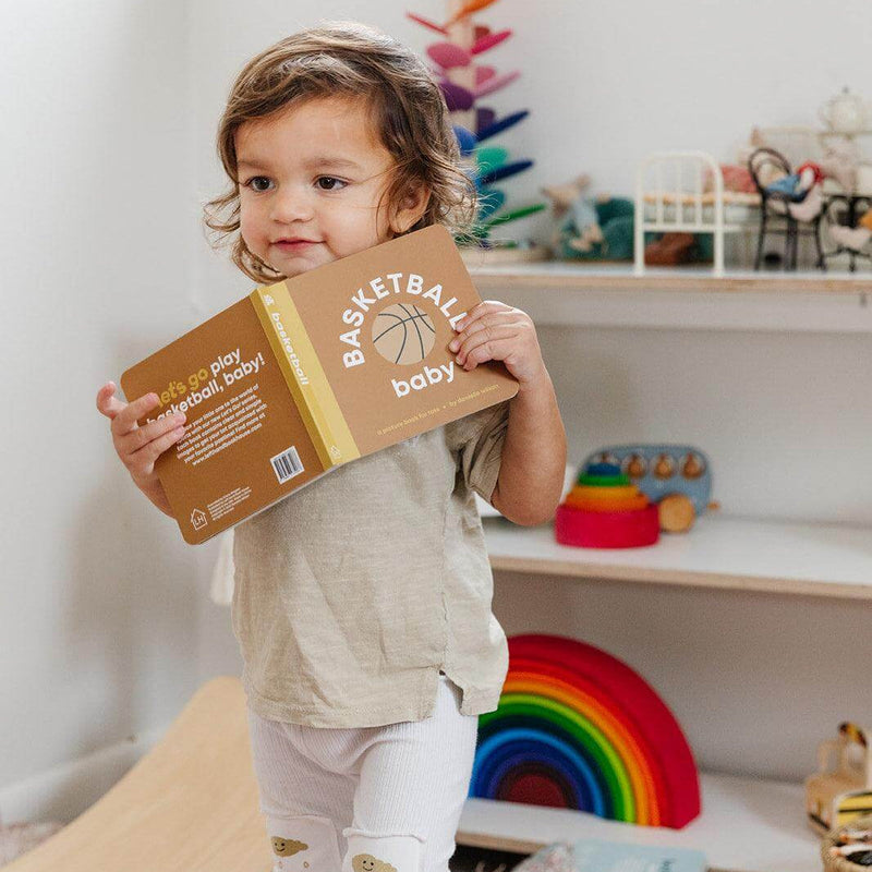 Toddler holding the Basketball Baby board book