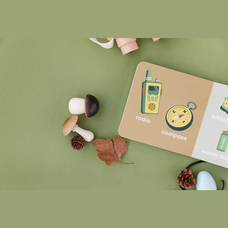 Mountain Baby board book open to the radio and compass pages with mushrooms and pinecones