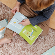 Toddler reading the Soccer Baby board book on a rug