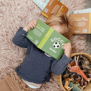 Toddler lying on a rug reading the Soccer Baby board book
