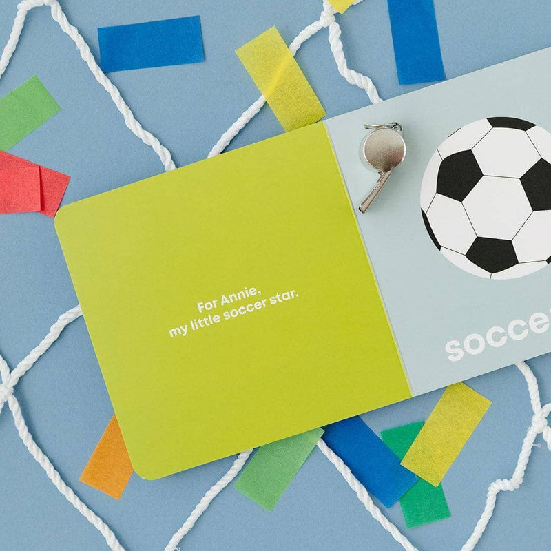 Soccer Baby board book open to the soccer ball page with confetti