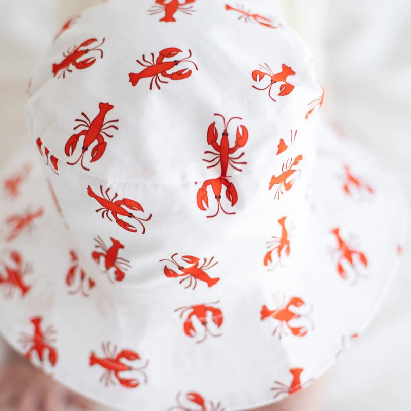 White baby romper with red lobster patterns on a white background