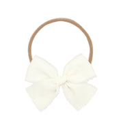 Cream-colored bow hair elastic on a white background