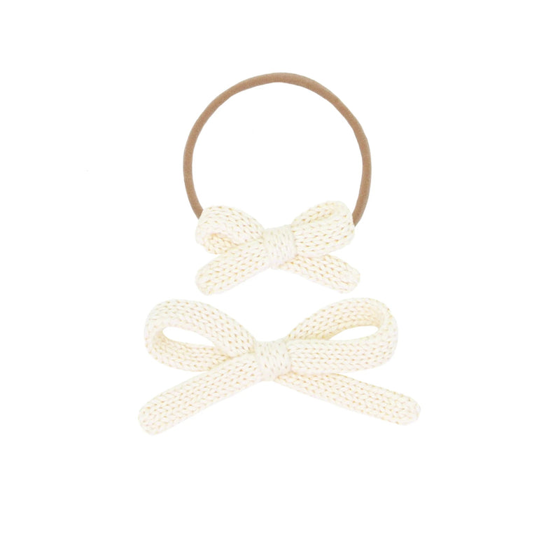 Two cream-colored bow hair ties on a white background