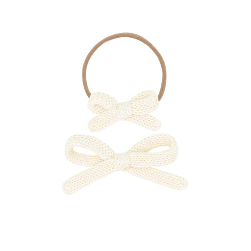 Two cream-colored bow hair ties on a white background