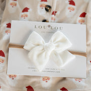 White bow headband on a Lou Lou & Co packaging with baby outfit in the background