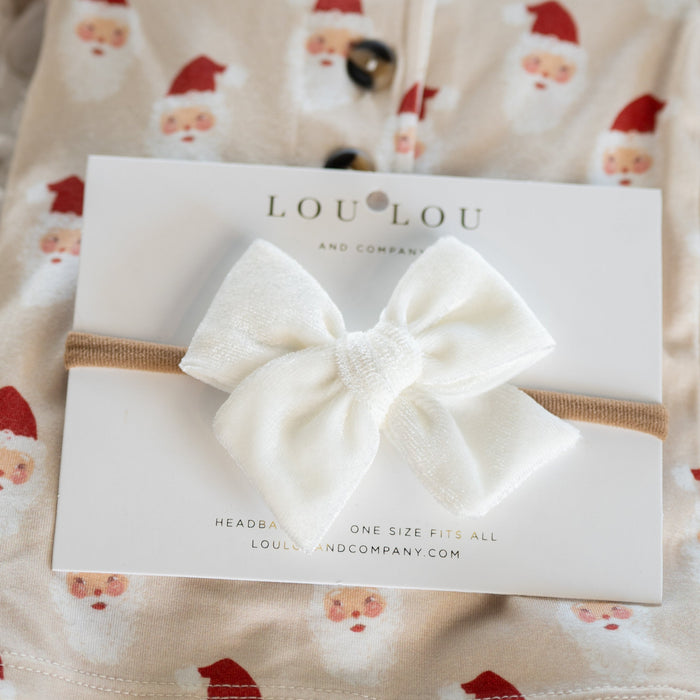 White bow headband on a Lou Lou & Co packaging with baby outfit in the background