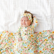 Baby in a floral outfit lying on a white textured surface