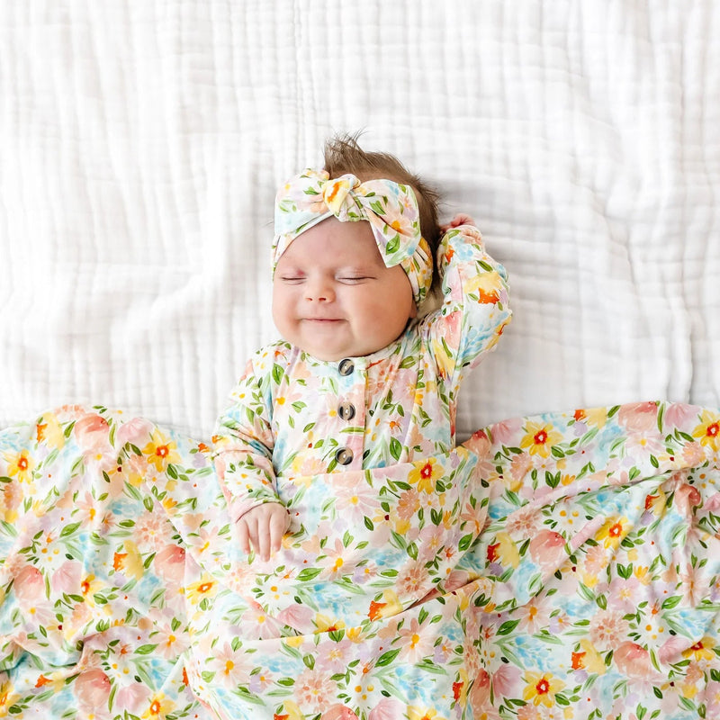 Baby in a floral outfit lying on a white textured surface