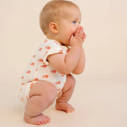 Baby in a patterned onesie on a beige background