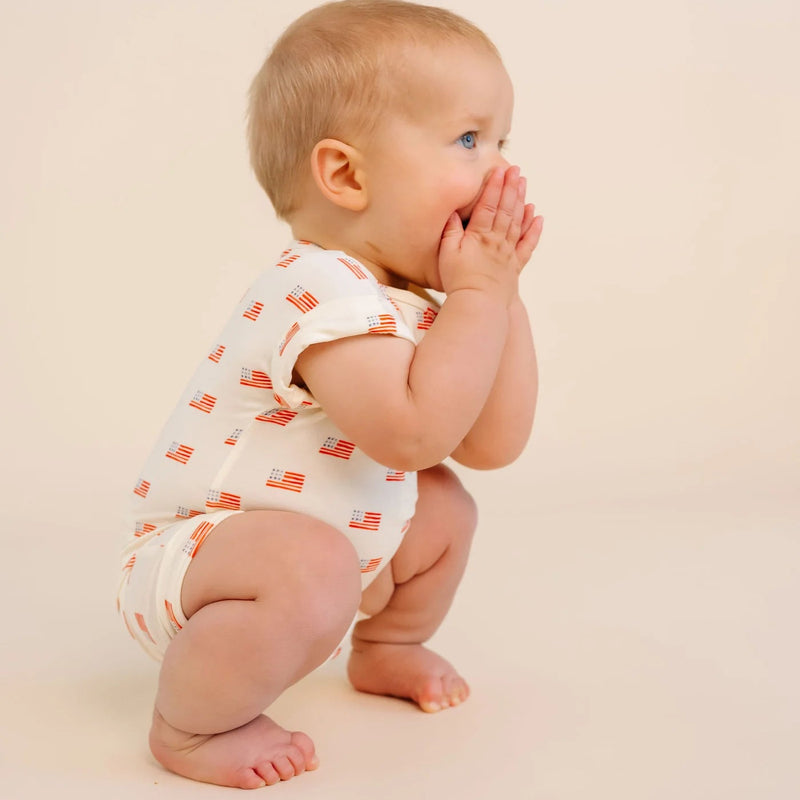 Baby in a patterned onesie on a beige background