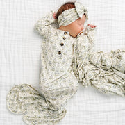 Newborn baby wrapped in a patterned swaddle on a white blanket