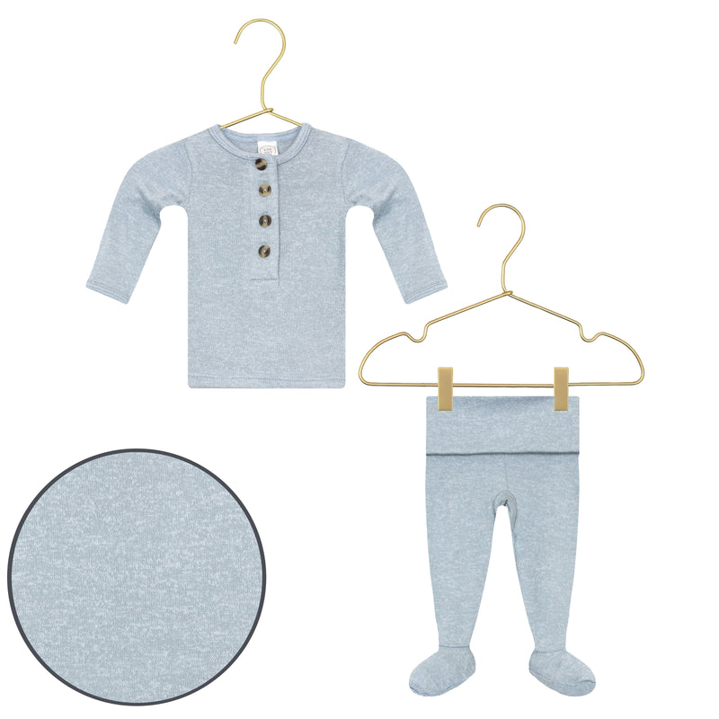 Baby outfit with long-sleeve shirt and footed pants on hangers against a white background.