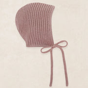 Knitted baby bonnet with a bow on a beige background