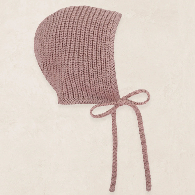 Knitted baby bonnet with a bow on a beige background